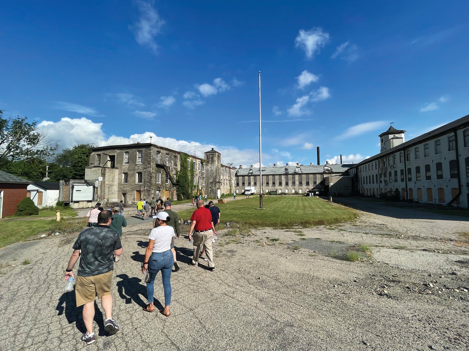 ‘CAMPUS-LIKE’: Participants in the site walk make their way to the courtyard in the middle of the main mill buildings at the Cranston Print Works site. Under the developer’s plan, parking spaces would fill the now-open space, while the surrounding buildings would be filled with apartments.